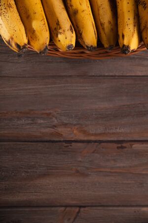 Bananas in a basket on a wooden brown natural background.の写真素材