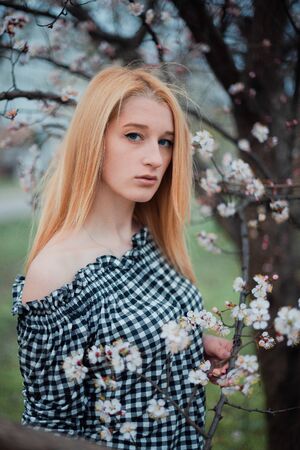 Beautiful young blonde girl on a background of flowering trees.の写真素材