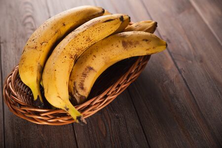 Bananas in a basket on a wooden brown natural background.の写真素材
