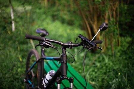 Mountain sports bike near a bench in a green park.の写真素材