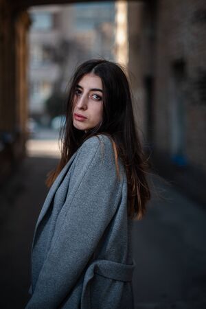 Girl in a red blouse and a gray cardigan on the background of the old brick wall.の写真素材
