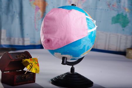 Globe in a medical mask on the background of a blurred world map concept of the global pandemic.の写真素材