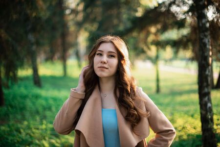 Beautiful young girl in a blue dress in a spring park.の写真素材