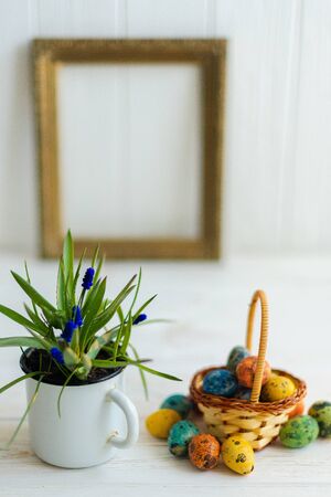 Multi-colored Easter eggs in a basket on a white wooden background.の写真素材
