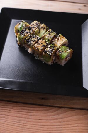Salmon sushi on a square black plate on a dark wooden background.の写真素材