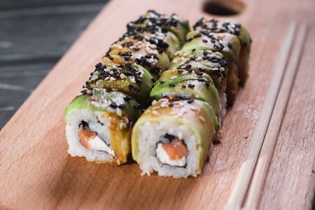 Sushi with salmon on a wooden board on a dark wooden background.の写真素材