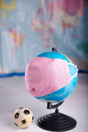 Globe in a medical mask with a soccer ball. The concept of canceling football matches due to coronavirus.の写真素材