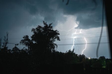Summer night thunderstorm with powerful lightning in the village.の写真素材