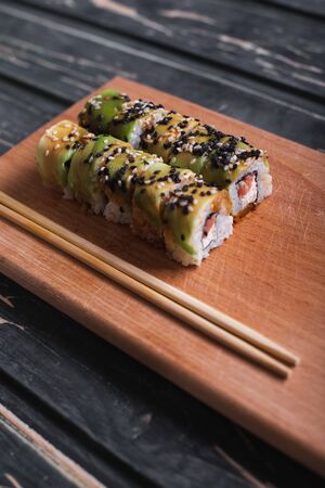 Sushi with salmon on a wooden board on a dark wooden background.の写真素材
