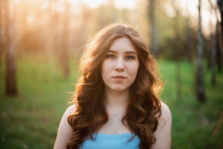 Beautiful young girl in a blue dress in a spring park.の写真素材