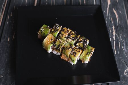 Salmon sushi on a square black plate on a dark wooden background.の写真素材