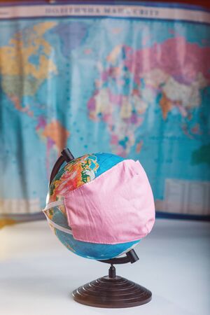 Globe in a medical mask on the background of a blurred world map concept of the global pandemic.の写真素材