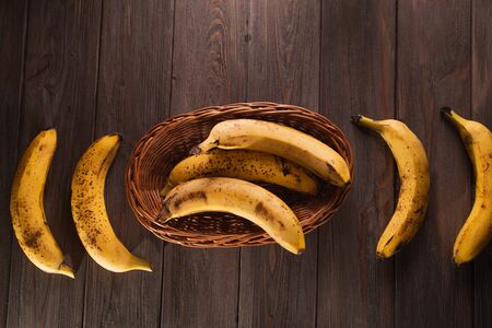 Bananas in a basket on a wooden brown natural background.の写真素材