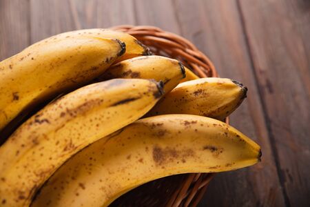 Bananas in a basket on a wooden brown natural background.の写真素材