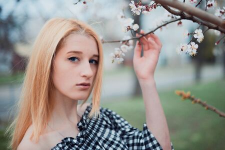 Beautiful young blonde girl on a background of flowering trees.の写真素材