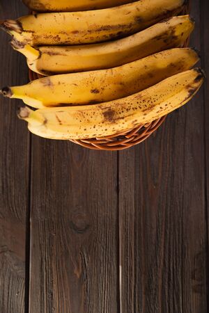 Bananas in a basket on a wooden brown natural background.の写真素材