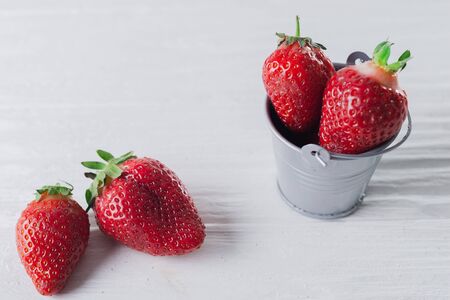 Juicy fresh Strawberries in a small iron bucket on a white wooden background.の写真素材