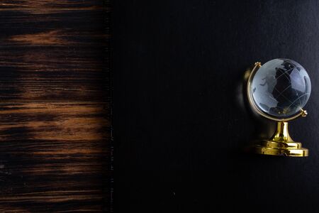 Glass globe on a black matte notebook on a wooden background.の写真素材