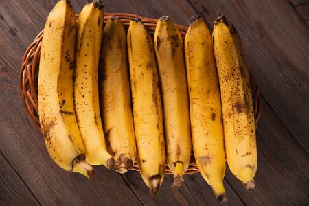 Bananas in a basket on a wooden brown natural background.の写真素材