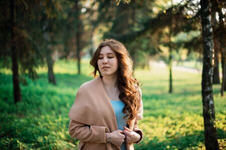 Beautiful young girl in a blue dress in a spring park.の写真素材