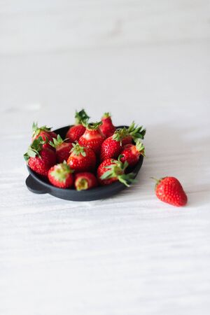 Fresh juicy strawberries in a black plate on a white background.の写真素材