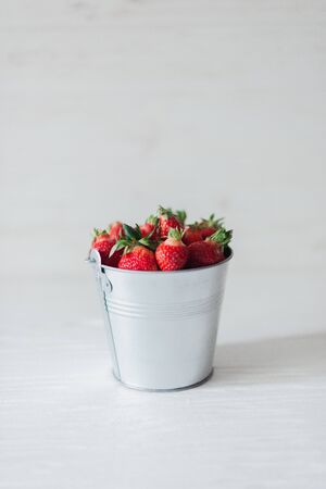 Juicy fresh strawberries in a metal bucket on a white background.の写真素材