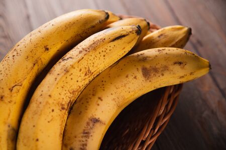 Bananas in a basket on a wooden brown natural background.の写真素材