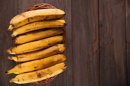 Bananas in a basket on a wooden brown natural background.の写真素材