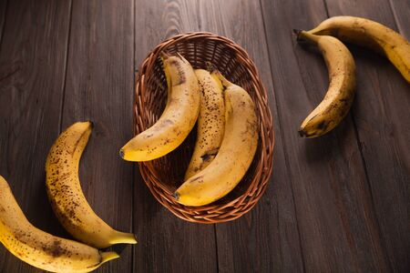 Bananas in a basket on a wooden brown natural background.の写真素材