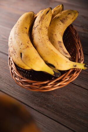 Bananas in a basket on a wooden brown natural background.の写真素材