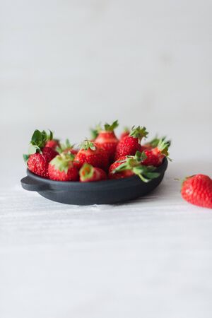 Fresh juicy strawberries in a black plate on a white background.の写真素材