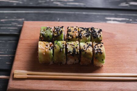 Sushi with salmon on a wooden board on a dark wooden background.の写真素材