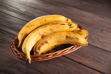 Bananas in a basket on a wooden brown natural background.の写真素材