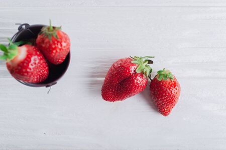 Juicy fresh Strawberries in a small iron bucket on a white wooden background.の写真素材