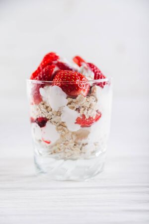 Strawberry dessert in a plate with ice cream and cream on a white wooden background.の写真素材