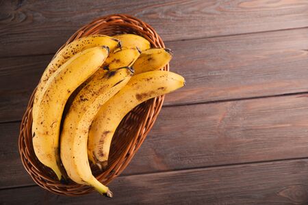 Bananas in a basket on a wooden brown natural background.の写真素材