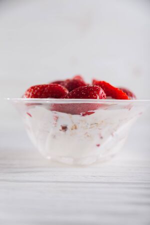 Strawberry dessert in a plate with ice cream and cream on a white wooden background.の写真素材