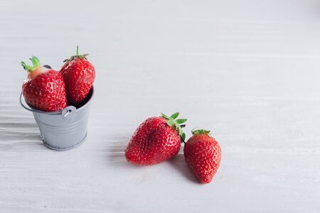 Juicy fresh Strawberries in a small iron bucket on a white wooden background.の写真素材