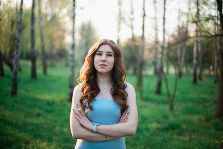 Beautiful young girl in a blue dress in a spring park.の写真素材