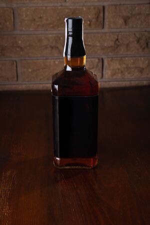 Bottle of brandy on a dark brick background.の写真素材
