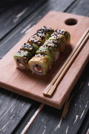 Sushi with salmon on a wooden board on a dark wooden background.の写真素材