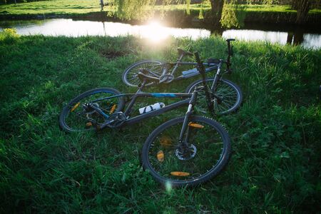 Two sports bikes on the grass near the river in the sunset sunlight.の写真素材