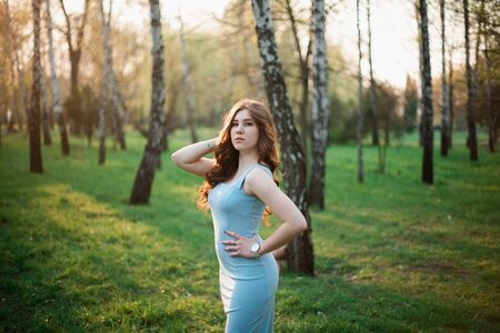 Beautiful young girl in a blue dress in a spring park.の写真素材