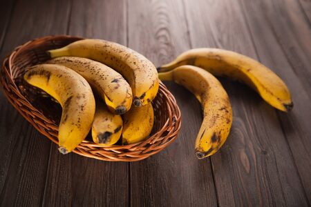 Bananas in a basket on a wooden brown natural background.の写真素材