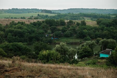 Summer landscape on a cloudy day. Mountain village near the pond.の写真素材