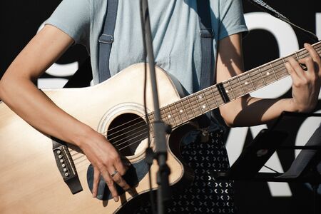 Girl with a guitar sings near the microphone.の写真素材