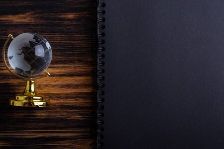 Glass globe on a black matte notebook on a wooden background.の写真素材