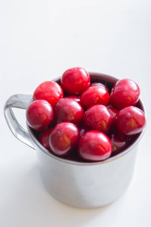 Sweet cherries in a steel mug on a white paper background.の写真素材