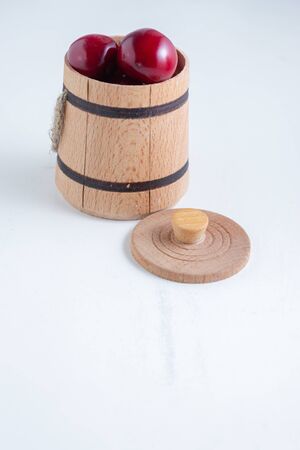 Sweet cherry berries in a wooden small barrel on a white background isolate.の写真素材