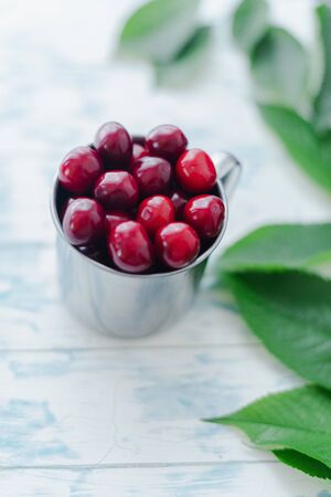 Cherries in a steel mug on a wooden background.の写真素材